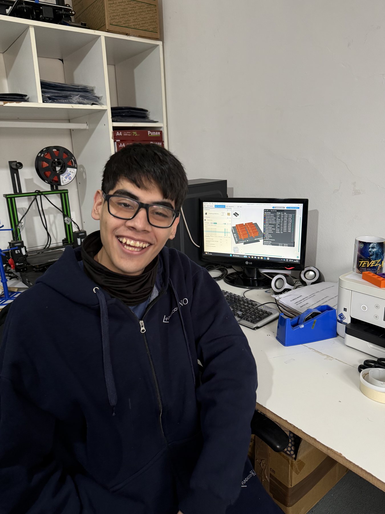Un alumno sonriendo frente a la computadora en el taller de tecnología.
